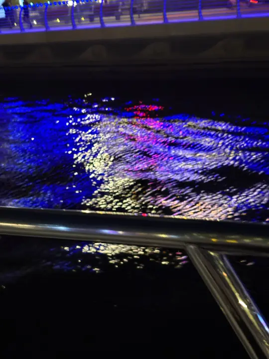 Blue, white and pink city lights reflected on dark water at night