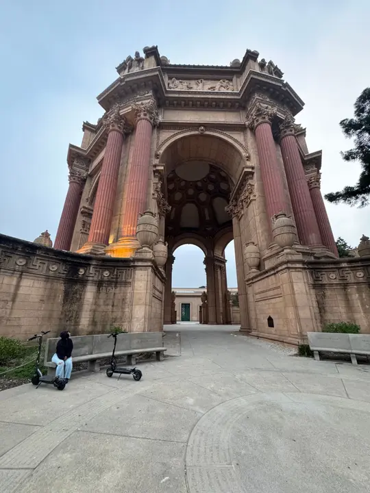 The Palace of Fine Arts rotunda in San Francisco, someone sitting on a bench beside two scooters